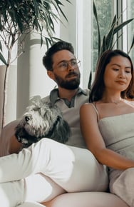 Två personer och en hund sitter i en soffa